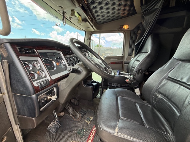Kenworth W900 truck interior showing steering wheel, dashboard with gauges, and driver seat.