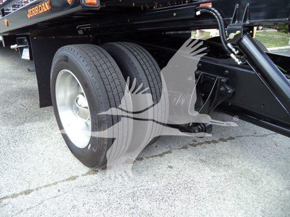 Dual rear wheels and chassis of a 2019 International DURASTAR 4300 tow truck showing heavy-duty axle and leaf springs.
