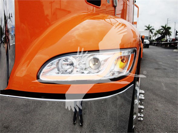Peterbilt 337 truck front-left view with orange paint, headlight assembly, chrome bumper, and wheel with dual tires in background.