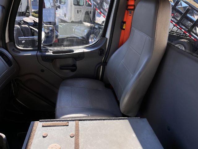 Cab interior of a 2015 Freightliner M2 chassis showing seat and window, with a metal compartment in foreground.