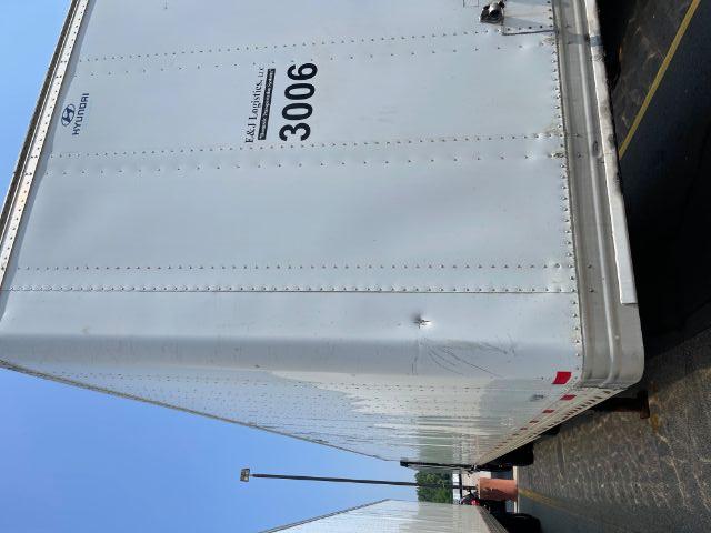 Hyundai trailer rear corner with number 3006 and E&J Logistics sticker, white riveted metal sides, bottom steelkick bumper, vertical lines.