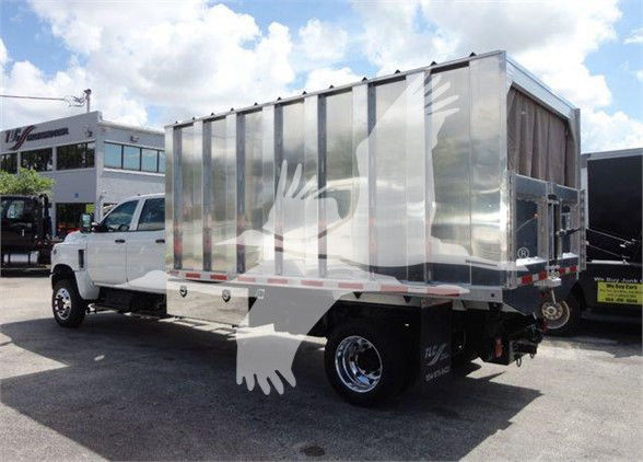Dump truck with aluminum cargo body showing side and rear. No visible license plate. Some faint text on rear reflectors and wheel area.