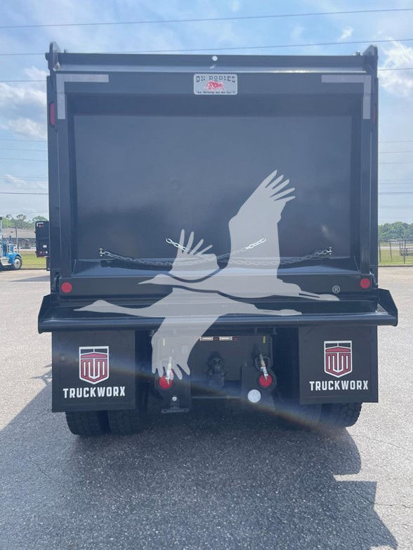 Kenworth T880 dump truck rear showing tailgate with a large graphic of white birds in flight and red taillights. Mudflaps read TRUCKWORX.