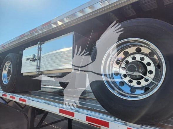 WABASH trailer flatbed showing spare tire, chrome wheel, side toolbox, and aluminum underbody with reflective striping.
