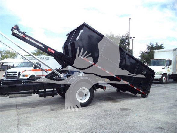 Side view of a 2015 Freightliner Business Class M2 106 dump truck with a raised black dump bed and hydraulic lift in a lot.
