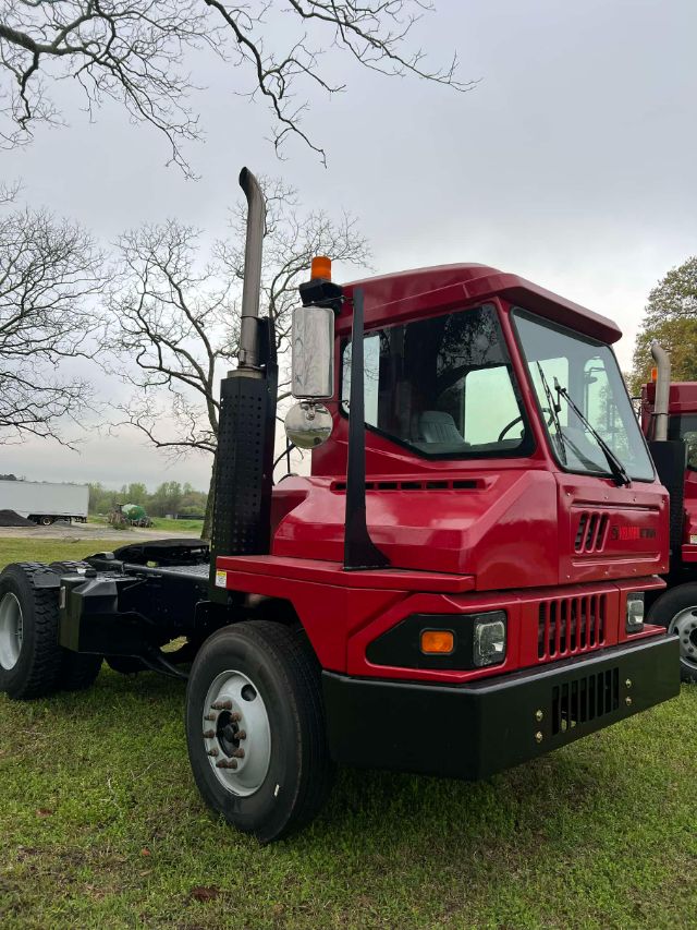 Red Kalmar Ottawa T2 yard truck cab front-left view with black bumper, vertical exhaust stack, and orange beacon.