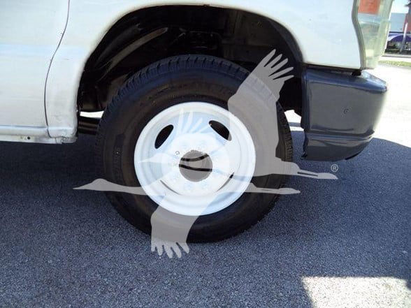 Ford E450 front wheel well and white steel wheel with tire, fender and bumper visible