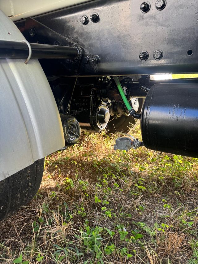 Freightliner 114SD undercarriage showing fuel tank, hydraulic lines, and chassis with bolts and frame rails.