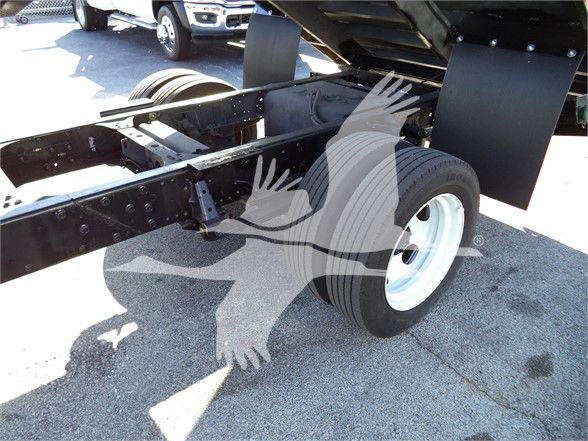 Isuzu truck chassis rear with single axle and large black dump bed, exposed frame rails and wheel, no cab visible.