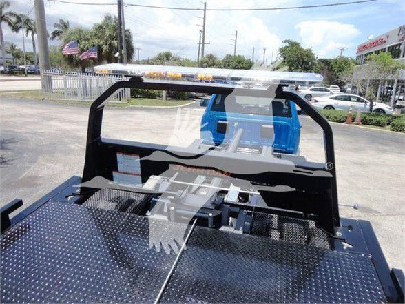 Ram 5500 tow truck bed with metal diamond-plate surface and blue seats in background.