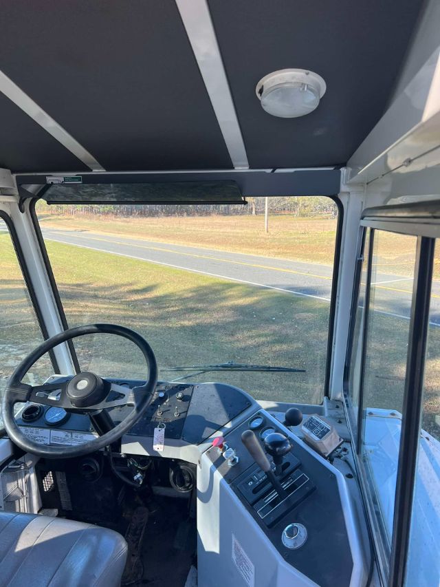 Cab interior of a 2012 Ottawa 4x2 CNG truck showing steering wheel, instrument cluster, control levers, and ceiling with a dome light.
