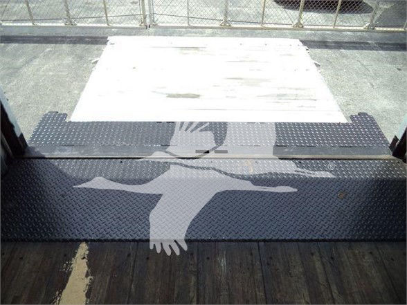 Platform entry with diamond plate steps and stairs, showing a loading dock area beyond a truck. Visible text is not legible; no fluid labels or part numbers clearly readable.