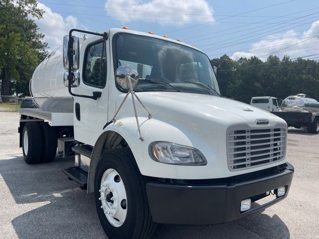 Freightliner M2 sewer service truck in white, front/driver side view with tank behind cab, large grille, rounded fenders, and side mirrors.