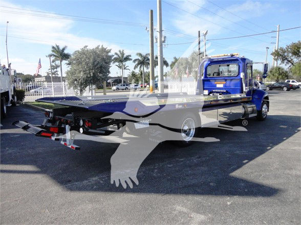 Peterbilt 337 tow truck flatbed with blue cab and long black flatbed, rear equipment visible