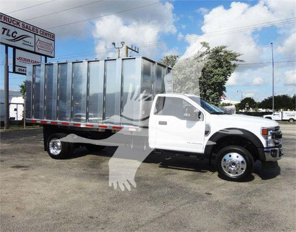 Ford F-550 dump truck with metal cargo bed and white cab, side view showing cargo area and dual rear wheels.