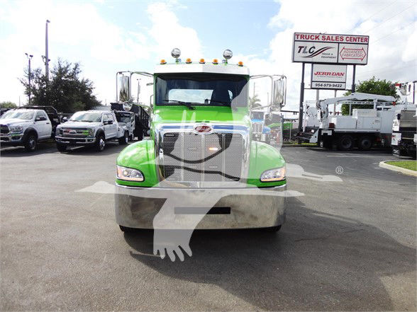 Front view of a bright green Peterbilt 337 truck with chrome grille and bumper in a dealership lot.