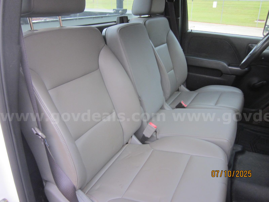 Front row of a 2017 Chevrolet Silverado 3500HD interior showing light gray cloth seats and front door panel.