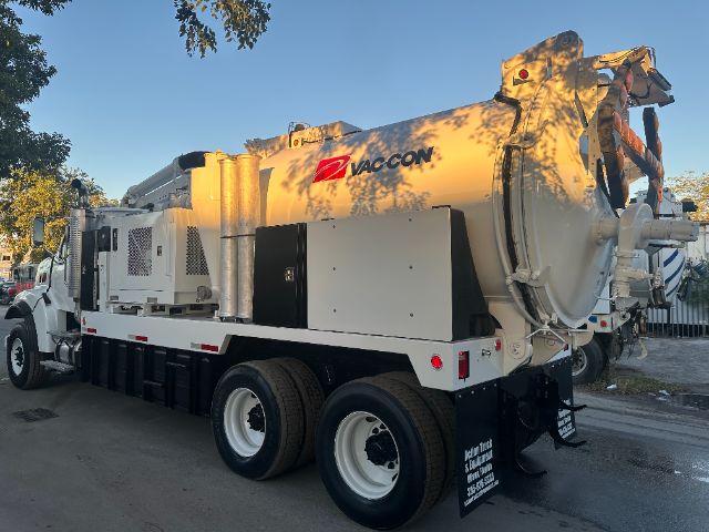 Vacuum truck rear-side view showing large cylindrical tank with Vac-Con logo, white chassis, dual rear axles, and equipment compartments.