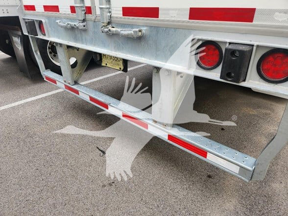 Rear view of a 2026 Wabash trailer with reflective red and white markings, taillights, and a metal bumper/step structure.