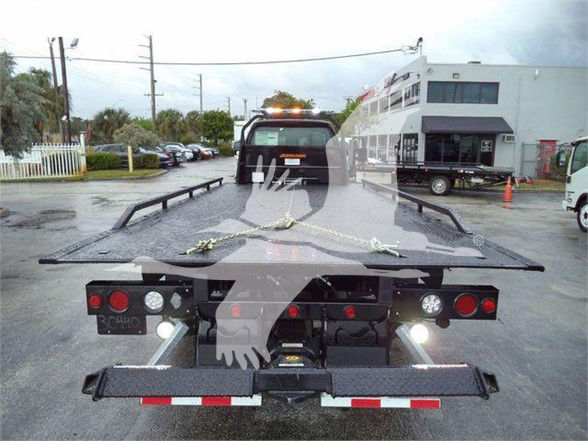 Ford F-750 SD flatbed tow truck rear view with ramps and lights.