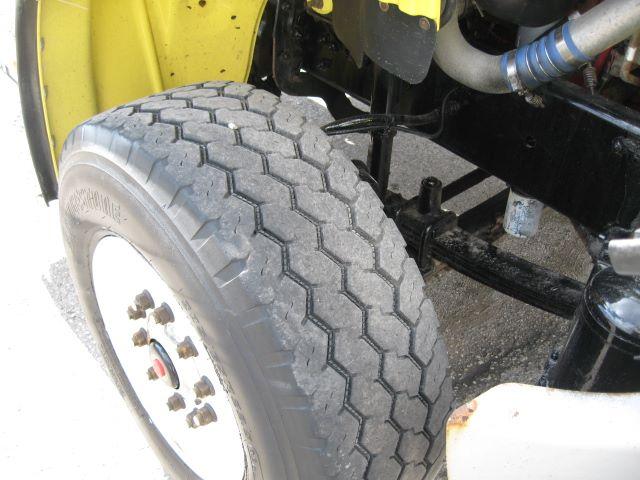 Freightliner M2106 front wheel and suspension showing tire tread, axle, and steering linkage in cab and chassis setup.