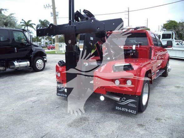 Tow truck with a red Ram 5500 Laramie, hitch/tow crane arm visible. Vehicle has stock number J40124 and VIN 3C7WRNEL5RG240124; dealership decals on front bumper with phone numbers.