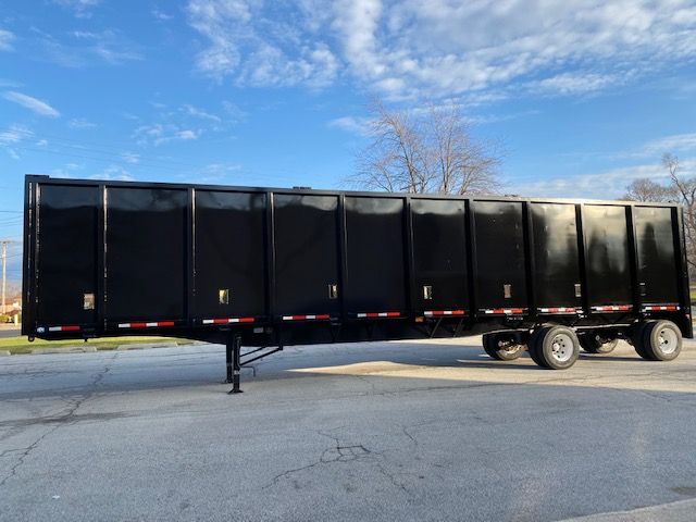 Crush car carrier trailer by Transcraft, 48 ft long, black, tandem axle with side doors and reflective tape along the lower edge.