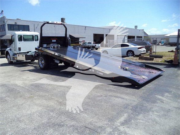 Kenworth T280 flatbed tow truck with a lowered heavy-duty ramp, front cab, and storage area in background.