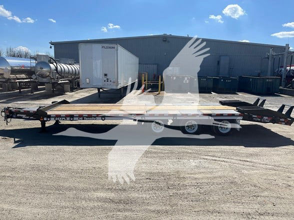 Eager Beaver 25Xpl trailer on a lot with a flatbed and equipment in background, side view showing tandem axles and low-profile rails.