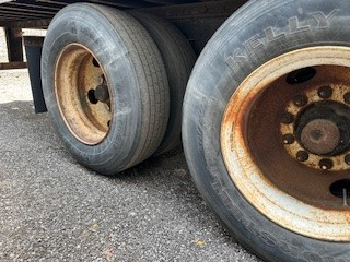 Two rear wheels of a trailer with worn rims and tires, showing the text 'KENWELL' on the tire sidewall.