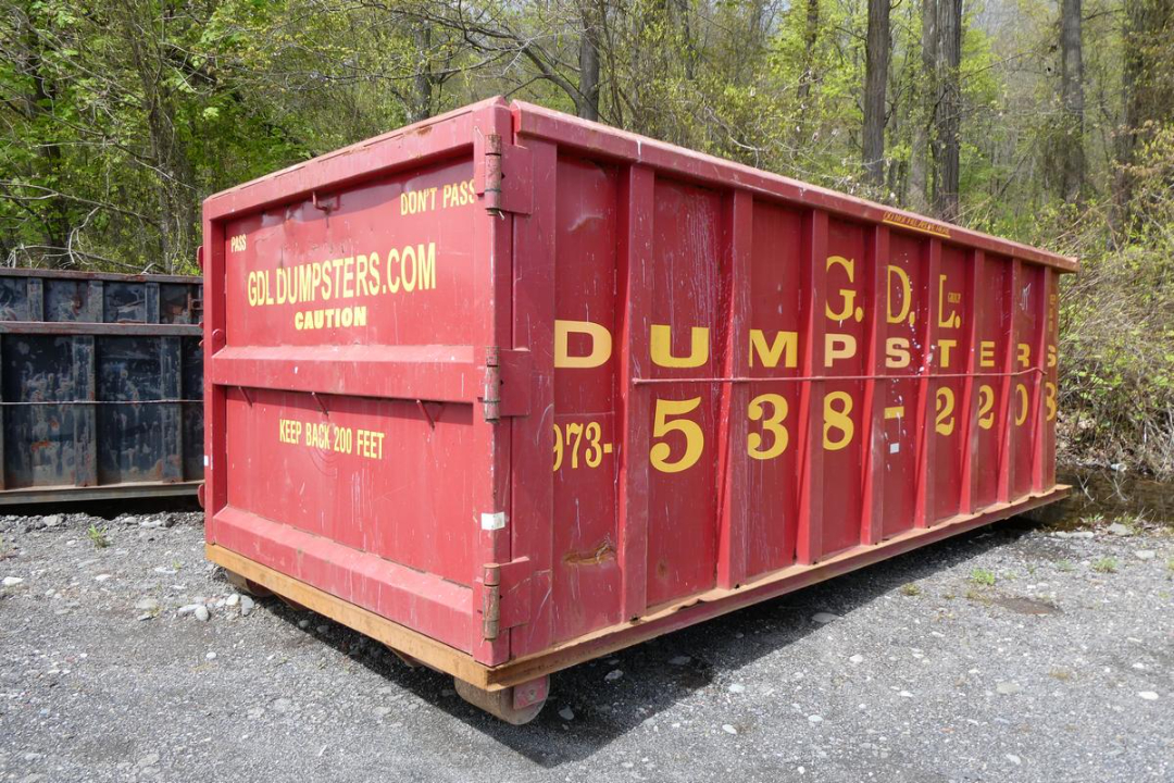 Red dumpster with yellow lettering: 'G D L DUMPSTERS' and large digits 538 on side; 'G D L DUMPS' across panels; warning texts 'KEEP BACK 200 FEET' and 'CAUTION'; left rear panel reads 'GDL DUMPSTERS.COM' and 'DONT PASS' 'CAUTION'
