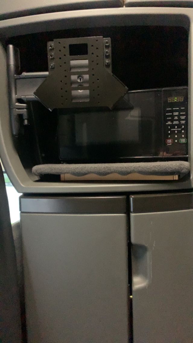 Interior of a 2019 Volvo VNL64T860 dash area showing a mounted screen with a bracket, microwave oven and surrounding storage panels.