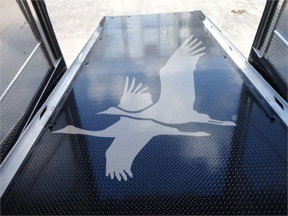 Image showing a steel diamond plate truck bed with a large white seagull graphic on the floor of a Mack MD6 tow truck interior.