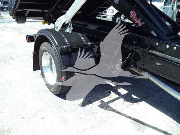Truck rear wheel and hydraulic arm of a refuse truck trailer with Bettigna script badge and hydraulic lines.