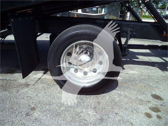 Wheel and tire on a flatbed truck trailer showing steel rim and black frame components.