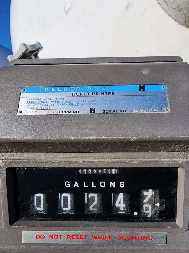 Veeders-Root Ticket Printer label with serial number plate above a Gallons meter showing 0024. Gallons reading 0 0 2 4 . 9? Do not reset while counting warning.