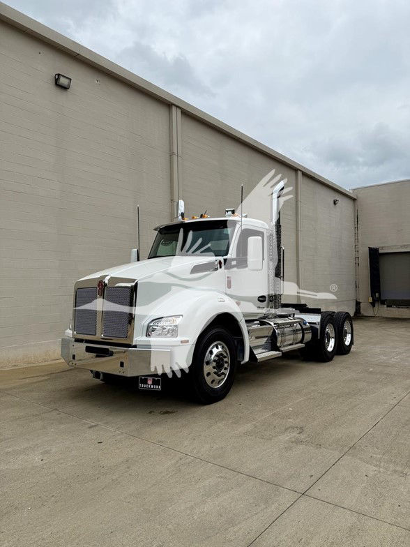 Kenworth T880 conventional daycab truck in white exterior, front grille, large fuel tanks, and dual rear axles. Visible: Kenworth truck with hood, headlights, and side mirrors.
