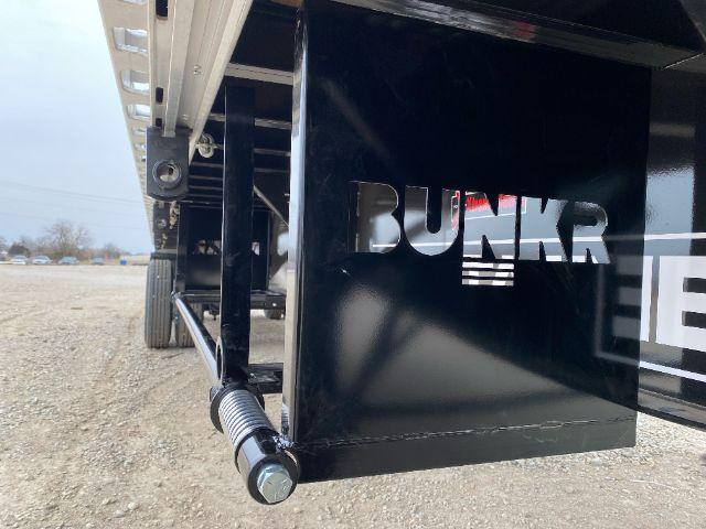 Trailer hitch area with a black metal panel showing the word 'BUNKR' in silver letters; visible spring-loaded jack foot and frame of trailer.