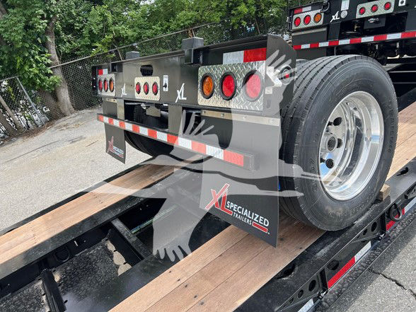 XL Specialized XL22FA lowboy trailer rear view showing spare wheel, taillights, and reflective tape; XL branding on mudflap.