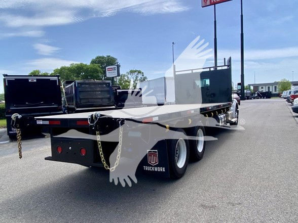 Kenworth T480 flatbed truck rear view showing dual rear axles and flatbed bed.