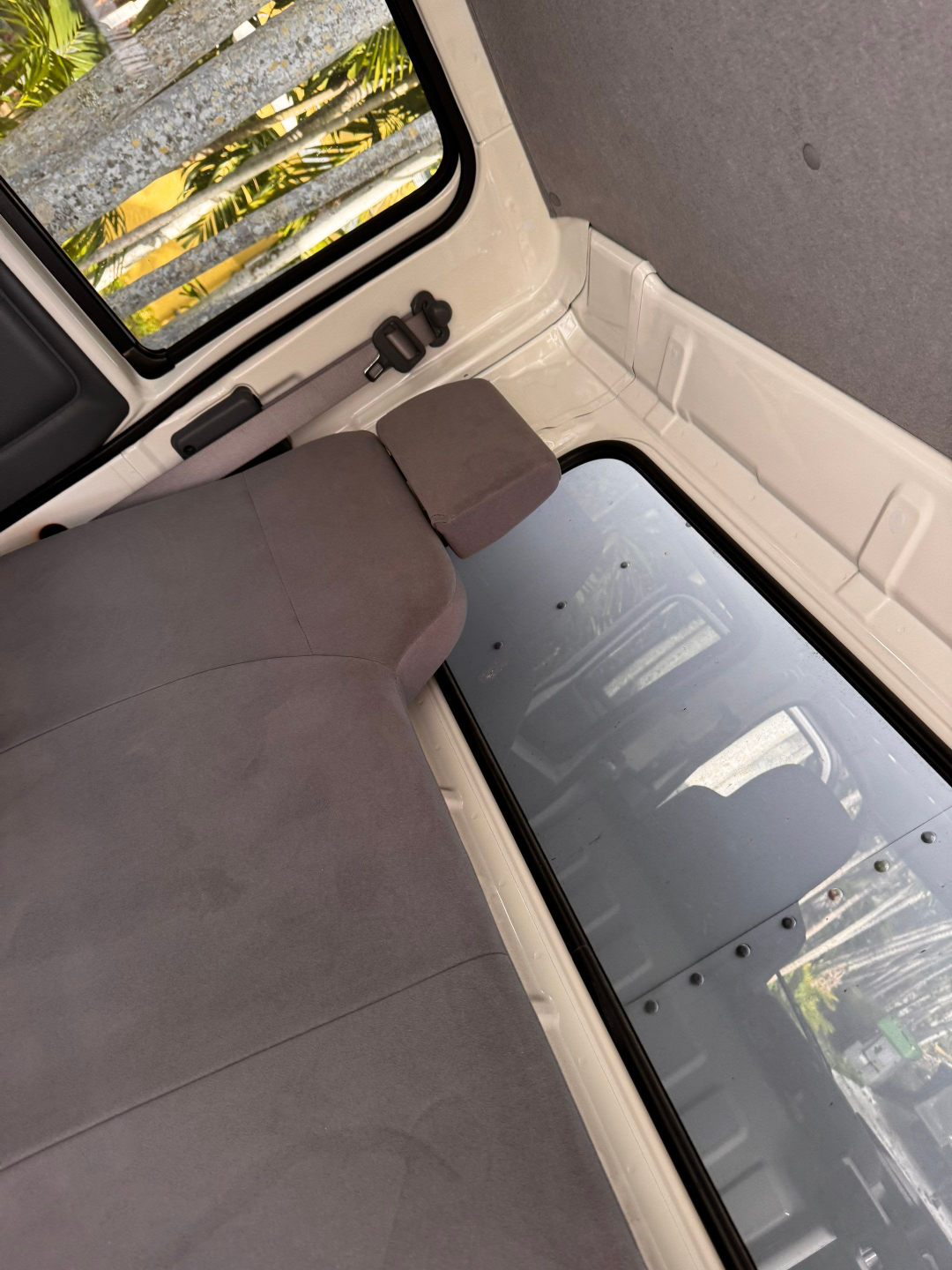 Isuzu NQR interior showing rear seating area and side window with latch and paneling.