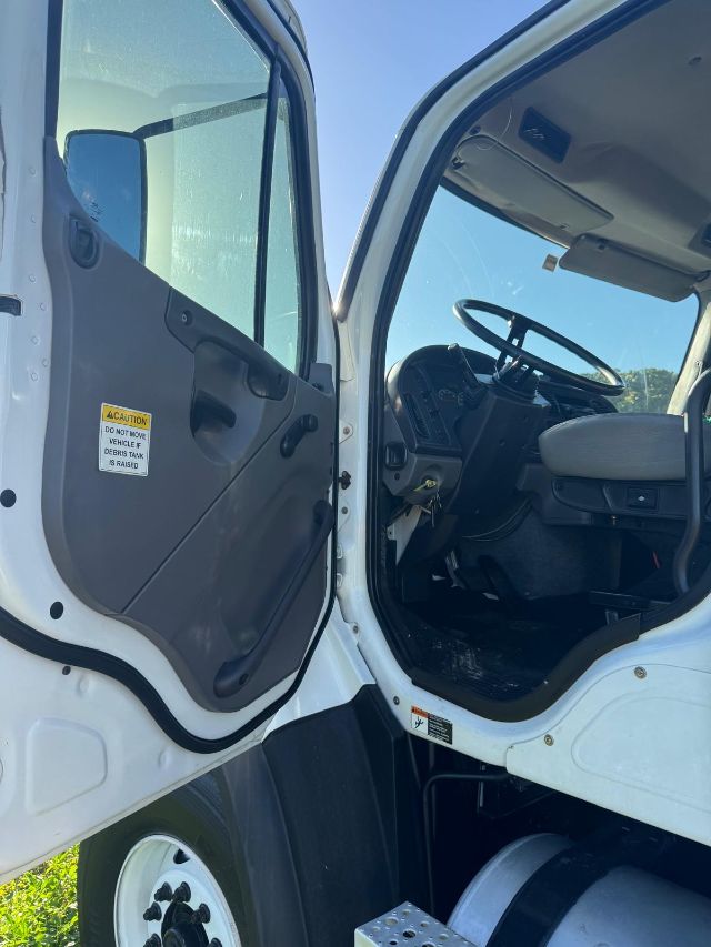 Truck cab interior of a 2014 Freightliner 114SD with open door showing driver seat, steering wheel, and dashboard.