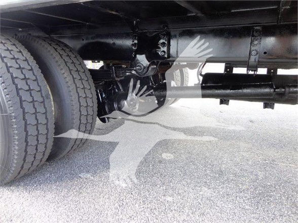 Underbelly of Freightliner truck showing rear dual wheels and drive shaft with label-like markings and piping along the chassis.
