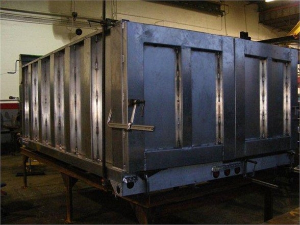 Dump body truck bed showing metal side panels and rear access door with latch, blue-gray finish.