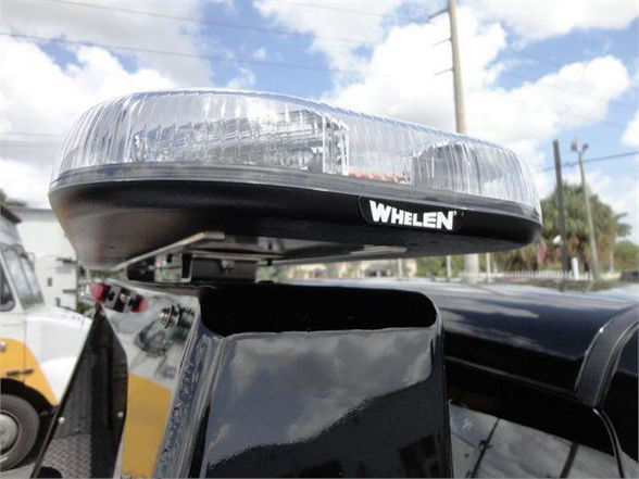 Ram 4500 tow truck with a Whelen rooftop light bar mounted on cab. Close-up shows light housing with clear lens and black base.
