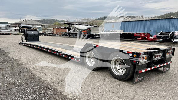 Flatbed trailer with dual rear wheels and long deck, side rails, and gooseneck hitch in a yard.