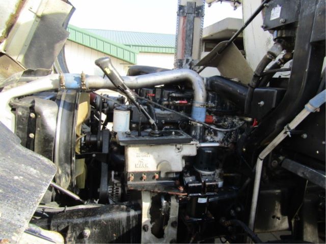 Engine bay of a 2003 Mack T310M showing fluid lines, hoses, and engine components in close view.