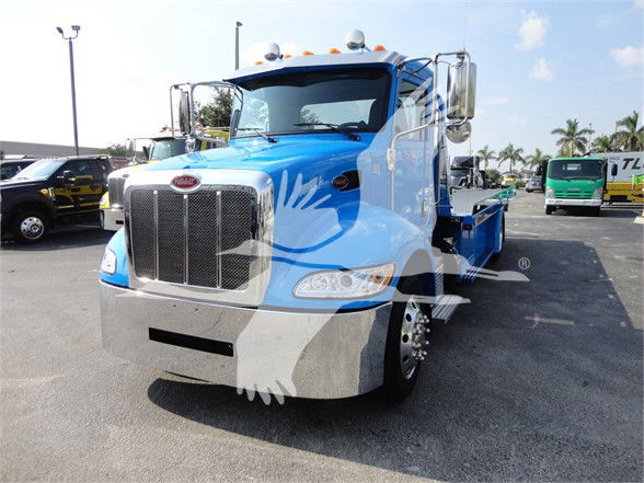 Blue 2022 Peterbilt 337 tow truck front view with chrome grille and large bumper.