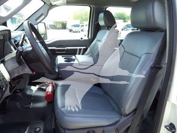Ford F-550 pickup interior showing front seats, steering wheel, center console, and steering column. Gray leather seats, cup holder area, and dashboard visible.
