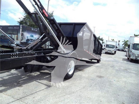 Freightliner BUSINESS CLASS M2 106 refuse truck body with lifting cargo bed and hydraulic arms, side view in a dealership yard.